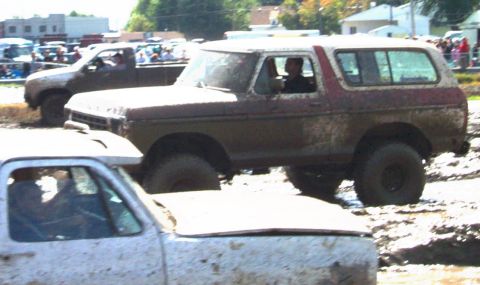 1979 Ford Bronco - A muddy 1978 Ford Bronco navigates a mud bog alongside other vehicles.