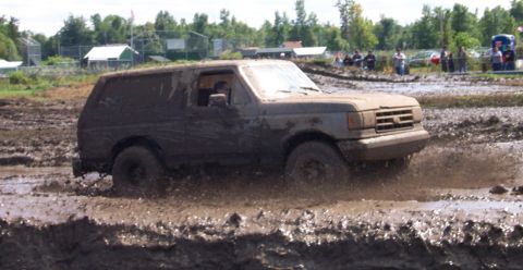 1979 Ford Bronco - This SUV is navigating a challenging mud course, with spectators in the background.