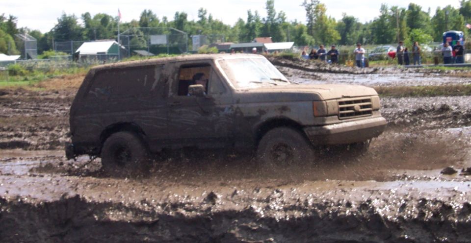 Muddy SUV driving through a mud pit, splashing mud