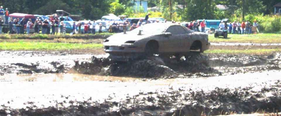 Mud-covered car stuck in mud pit