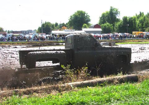 1979 Ford Bronco - Pickup truck participating in a mud bog event, covered in mud.