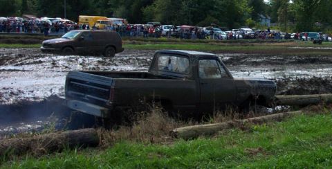 1979 Ford Bronco - Mud bogging event with trucks and SUVs stuck in mud, spectators in background.