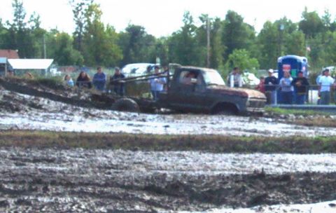 1979 Ford Bronco - A truck is stuck in a mud bog with spectators gathered around.