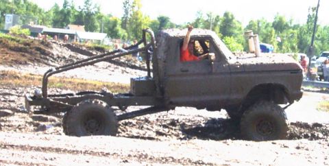 1979 Ford Bronco - This modified 1979 Ford Bronco is participating in a mud bogging event, event, with its driver giving a thumbs up.