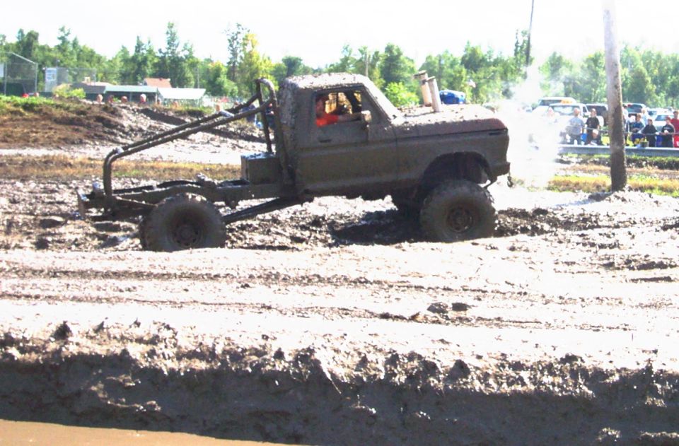 Mud-covered truck with roll cage and exhaust stack in a mud pit