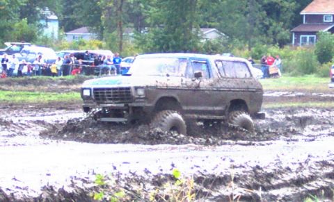 1979 Ford Bronco - This SUV is deep in the mud during a bogging event, with onlookers watching from the side.