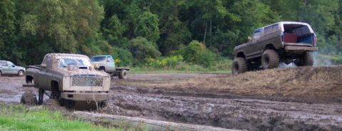 1979 Ford Bronco - Multiple off-road vehicles navigate a challenging muddy terrain during an event.