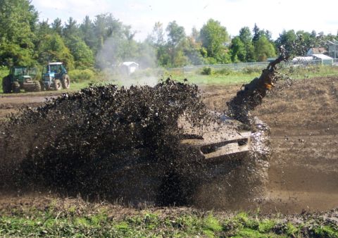 1979 Ford Bronco - A vehicle is submerged in a mud pit, with two tractors visible in the background.