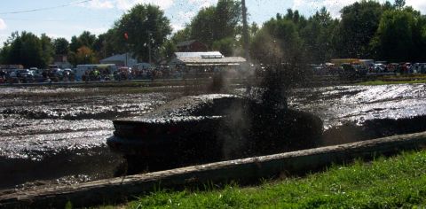1979 Ford Bronco - A 1978 Ford Bronco is stuck in a mud pit, with spectators and other vehicles in the background.