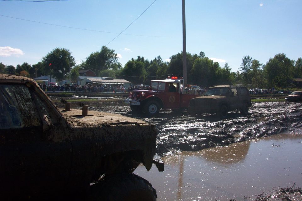 Muddy vehicles in a mud bog with spectators watching
