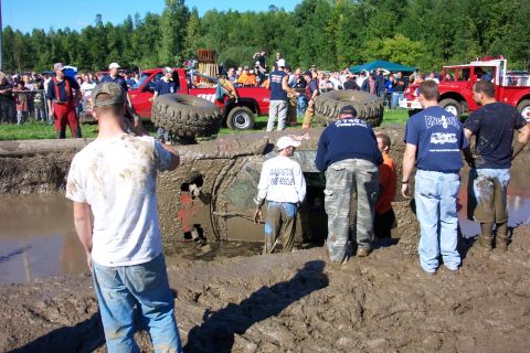 1979 Ford Bronco - Spectators watch as a vehicle is submerged in mud during an off-road event.