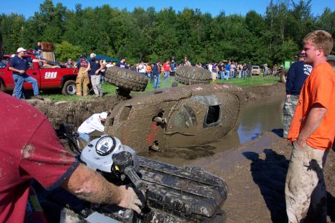1979 Ford Bronco - A muddy scene unfolds as a vehicle is stuck in a mud pit, with onlookers and a rescue truck present.