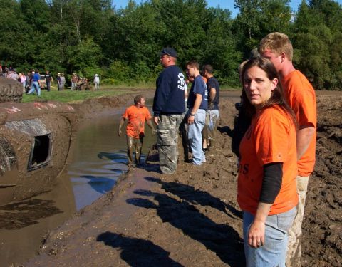 1979 Ford Bronco - Spectators watch as a vehicle is stuck deep in a mud pit during an off-road event.
