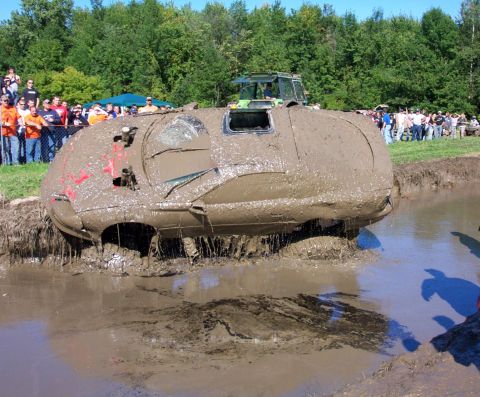 1979 Ford Bronco - Spectators watch as a vehicle is stuck deep in mud during a bogging event, with a tractor nearby.