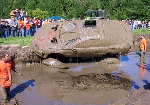 1979 Ford Bronco - A vehicle is submerged in mud during an off-road event, with onlookers gathered to observe the scene.