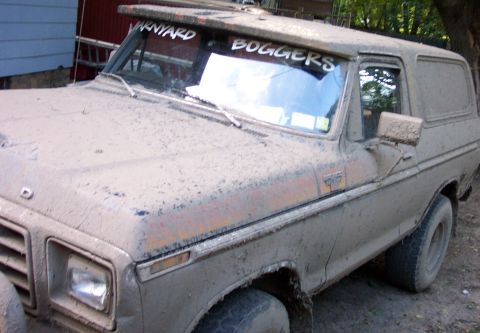 1979 Ford Bronco - This heavily soiled 1978 Ford Bronco is viewed from the front three-quarter angle, revealing its weathered condition and custom windshield…