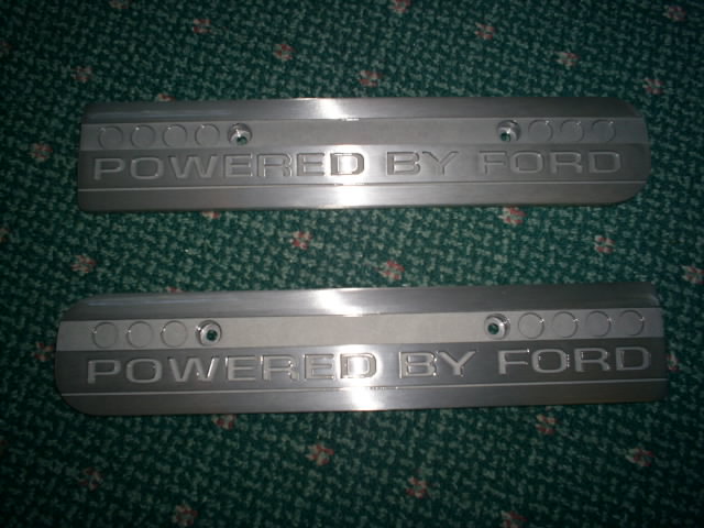 Two aluminum engine coil covers with 'POWERED BY FORD' engraved