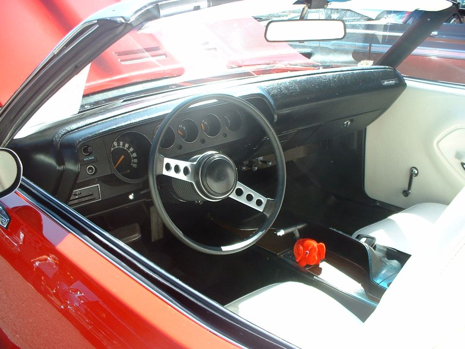 Red convertible interior with black dashboard, white seats, and a three-spoke steering wheel