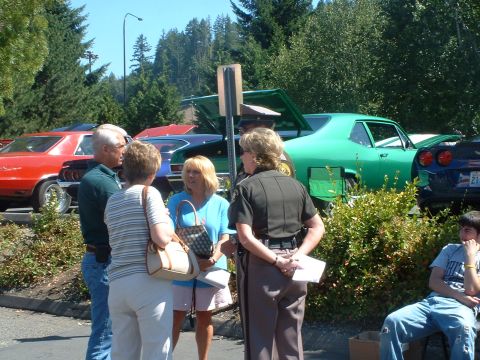 2000 Ford Crown Victoria - Several vehicles and people are gathered at an outdoor event on a sunny day.