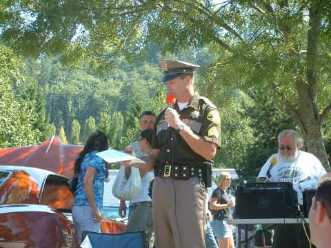 2000 Ford Crown Victoria - A sheriff addresses a crowd at an outdoor event with vehicles visible.