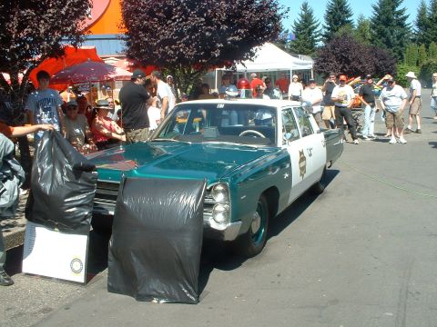 2000 Ford Crown Victoria - A vintage police car is displayed outdoors with people gathered around.