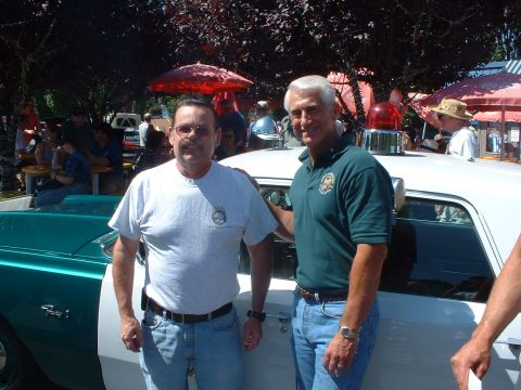 2000 Ford Crown Victoria - A vintage police car is displayed at an outdoor event with two men posing beside it.