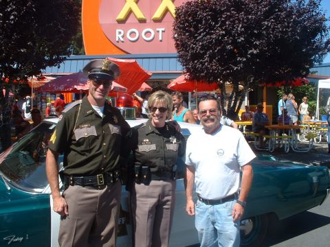 2000 Ford Crown Victoria - Two officers pose with a civilian next to a 1967 Plymouth Fury I, likely a King County Sheriff's unit.
