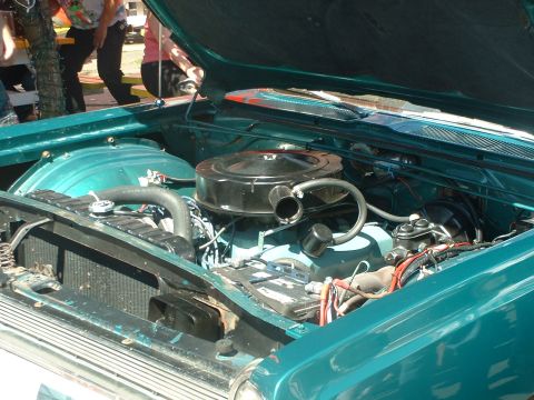 2000 Ford Crown Victoria - The engine bay of a classic teal car is visible with the hood raised.