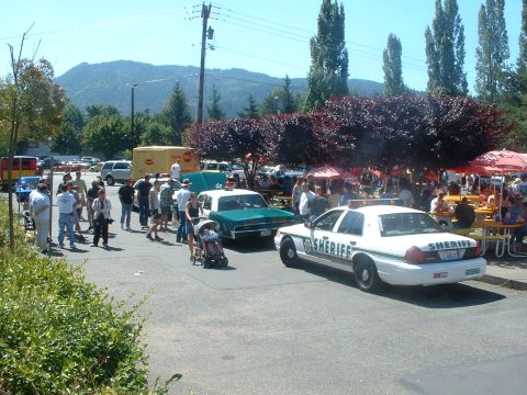 2000 Ford Crown Victoria - A Sheriff's car is parked at an outdoor gathering with many people milling about and other cars present.