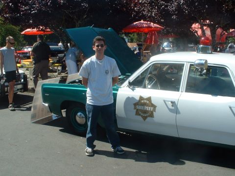 2000 Ford Crown Victoria - A man stands next to a vintage King County Sheriff's car with its hood open at an outdoor event.