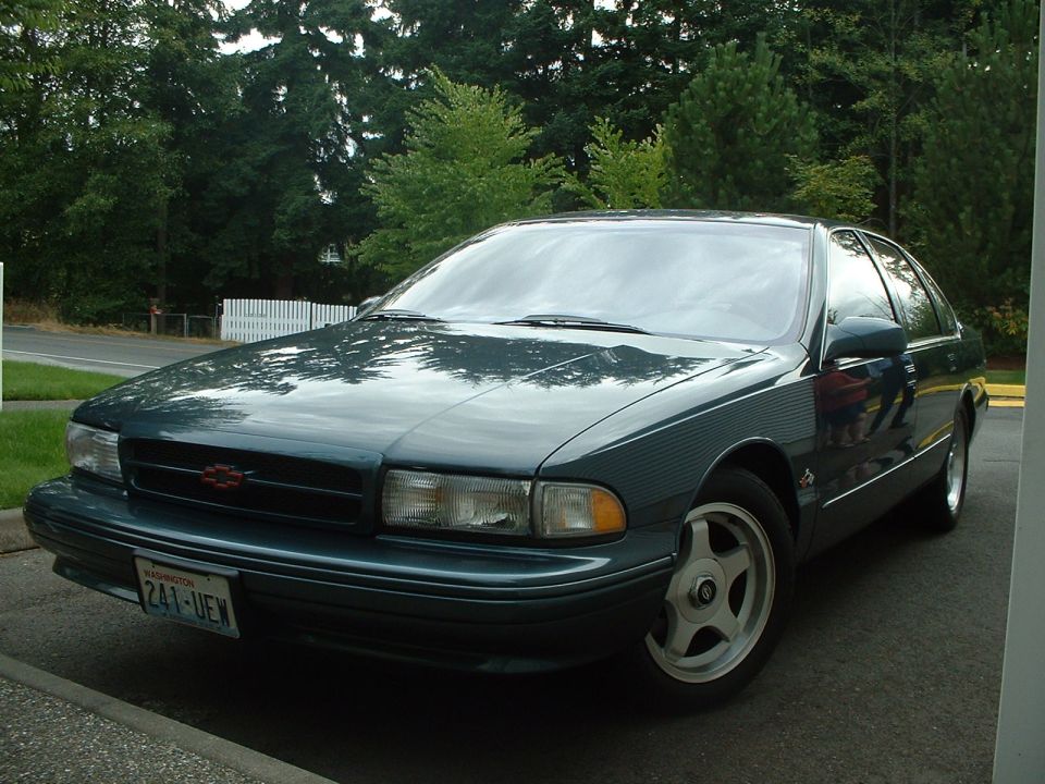 Dark green sedan with a red Chevrolet badge on the grille, parked on a paved surface
