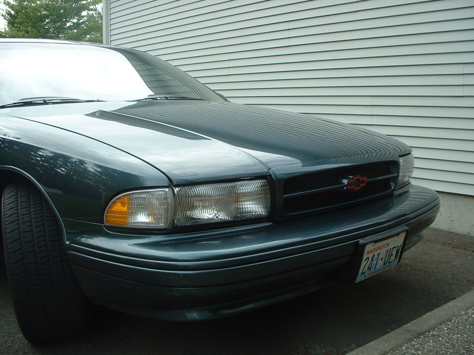 Dark green 1994 Chevrolet Impala front end with red Chevrolet emblem on grille