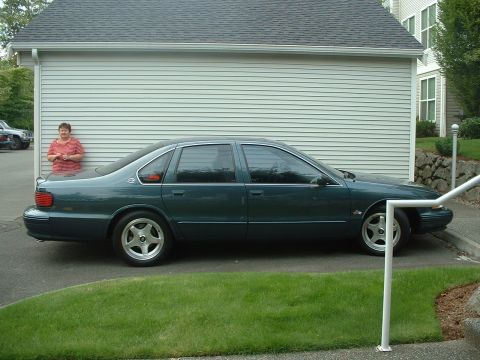 2000 Ford Crown Victoria - Side view of a green 1996 Chevrolet Impala SS sedan parked in front of a garage.