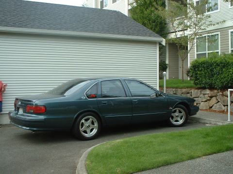 2000 Ford Crown Victoria - A sedan with a distinctive body style is parked on a paved surface next to a building.