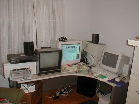 1999 Ford Crown Victoria - A desk scene multiple computer monitors, keyboards, a VCR, and speakers, suggesting a home office or entertainment setup.