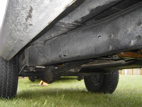 1977 Jeep Wagoneer - Underside view of vehicle frame, leaf springs, and rear axle with tires.