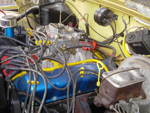 Engine bay showing carburetor, spark plug wires, and brake fluid reservoir