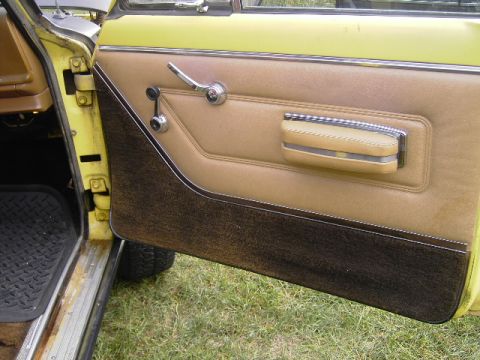 1977 Jeep Wagoneer - Close-up of a vintage Jeep Wagoneer's interior door panel, showing tan upholstery and chrome accents.
