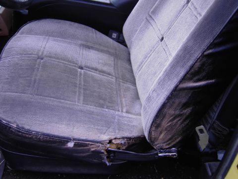 1977 Jeep Wagoneer - The driver's seat shows significant wear and tear, with fabric ripped and foam exposed.