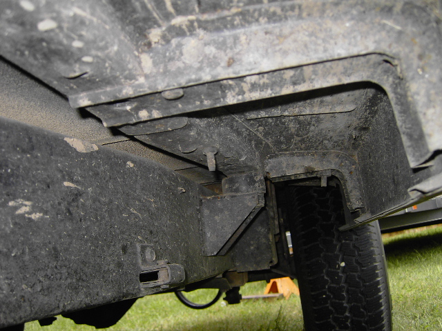 Close-up of vehicle frame and tire, showing suspension components and undercarriage. Supermotors.net logo visible