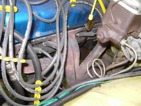 1977 Jeep Wagoneer - Close-up of engine components including spark plug wires and exhaust manifold.