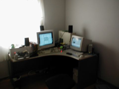 1999 Ford Crown Victoria - A cluttered desk setup features two CRT monitors, keyboards, and speakers, suggesting an older computer workstation.