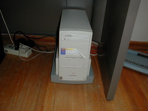 1999 Ford Crown Victoria - A Packard Bell desktop computer tower sits on a wooden floor next to a power strip.