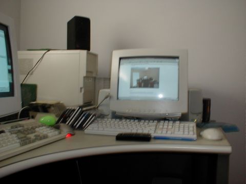 1999 Ford Crown Victoria - A cluttered desk features multiple computer components and a green mouse.