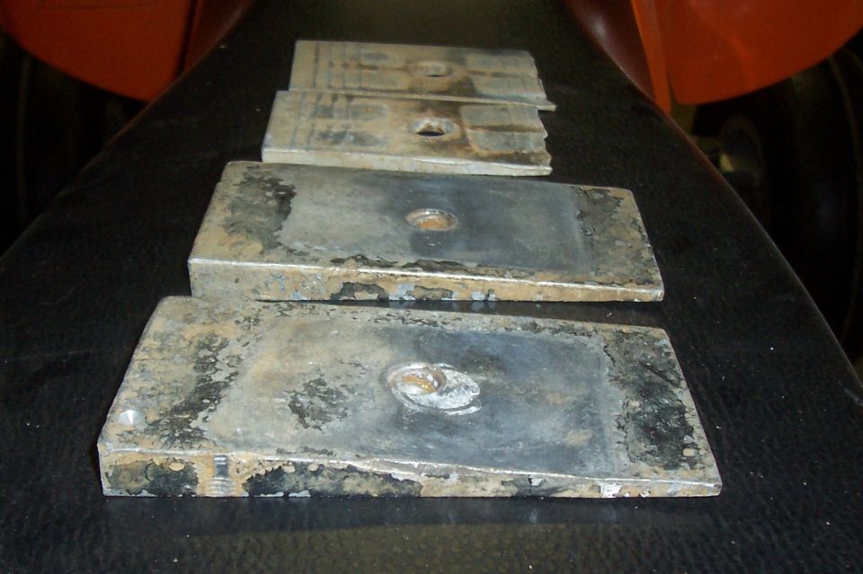 Four metal lift blocks with center holes, some rust and wear