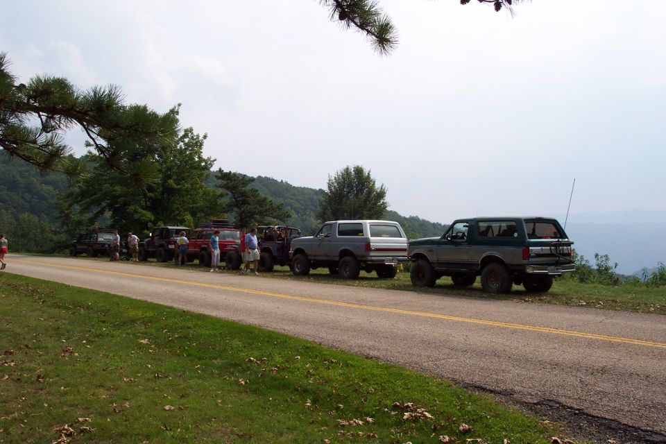 Several Ford Broncos parked on the side of a road with a scenic overlook