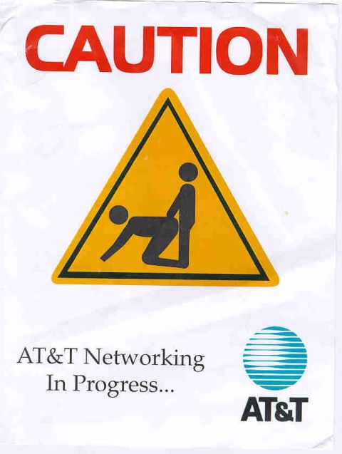 1999 Ford Crown Victoria - A humorous caution sign with a graphic and AT&T branding indicates 'AT&T Networking In Progress'.