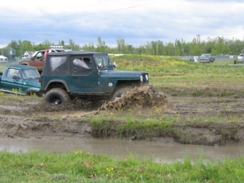 1978 Ford Bronco - Multiple off-road vehicles navigate a muddy track under a cloudy sky.