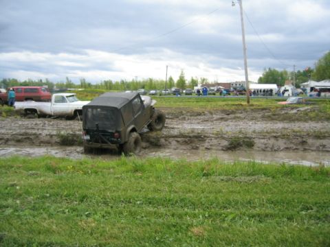 1978 Ford Bronco - Multiple vehicles are stuck in a muddy off-road course under a cloudy sky.