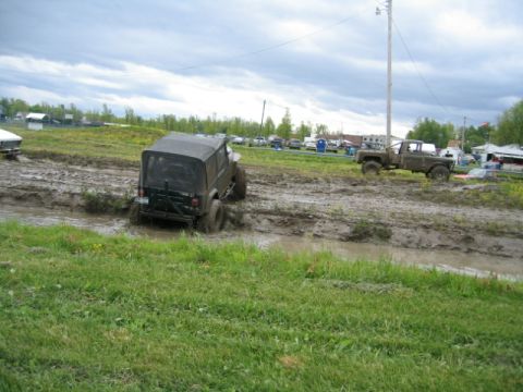 1978 Ford Bronco - Two off-road vehicles navigate a muddy track under a cloudy sky.